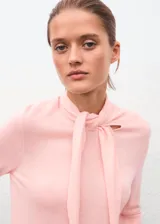 Jersey de punto fino color rosado, con cuello alto y cierre de nudo ajustable, de diseño recto y manga larga.