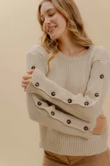 Sweater color camel de tejido de punto acanalado, con cuello redondo y botones decorativos en las mangas. Hecho en Uruguay.