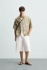 Camisa de manga corta y corte relajado confeccionada en tejido de algodón con diseño jacquard floral. Presenta cuello bowling, un bolsillo de plastrón en el pecho y cierre frontal con botones.