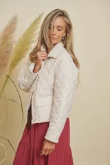 Campera matelasse impermeable color crudo, con cierre frontal, cuello y puños de pana. Presenta bolsillos frontales con solapa y botón.
