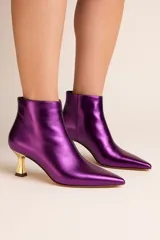 Botines de cuero sintético metalizado color violeta con punta fina y tacón dorado geométrico.