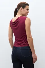 Top sin mangas color bordó, con escote asimétrico drapeado y ajuste al cuerpo.
