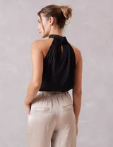 Blusa de satén color negro con diseño plisado, cuello alto tipo halter y corte sin mangas.