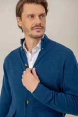 Sweater de lana lambswool color gris, con cuello alto, cierre frontal de botones y dos bolsillos delanteros tipo parche.