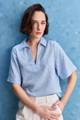 Blusa celeste de manga corta con cuello camisero y escote en V, confeccionada en tejido liviano con textura sutil y estampado de lunares.