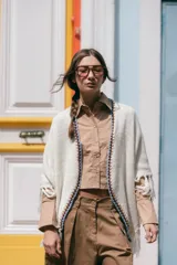 Poncho liviano de tejido de punto color blanco, con bordes decorados en crochet multicolor y flecos en el ruedo.