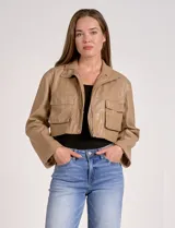 Chaqueta corta de eco cuero color tostado, con cuello alto, cierre frontal con botones a presión y bolsillos de solapa en el pecho. Tiene forro interno a tono.