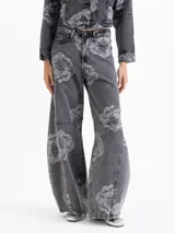 Pantalon de denim con lavado gris y estampado floral en contraste. De tiro medio y pierna amplia, presenta un calce relajado, bolsillos clásicos y cierre con botón metálico.