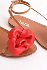 Sandalias bajas color cuero con tiras finas y aplique de flor dorada.