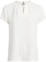 Blusa blanca de poliéster reciclado con cuello redondo, mangas cortas y cierre con cremallera en la espalda. Presenta una abertura en la parte delantera con barra metálica.