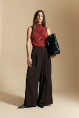 Top sin mangas de color negro con cuello alto y diseño drapeado en el frente. Confeccionado en una tela suave con acabado levemente satinado y silueta fluida.