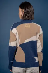 Buzo de punto con diseño abstracto que simula un paisaje, cuello redondo y mangas largas. Confeccionado en lana, presenta una combinación de colores en tonos beige, celeste y gris.