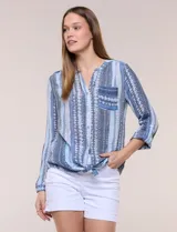 Blusa estampada Zac & Rachel de manga larga con cuello en V, cierre frontal con botones y bolsillo aplicado en el pecho. Presenta diseño a rayas verticales con motivos geométricos en tonos azules y celestes, con terminación anudada en el frente.