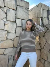Sweater marrón con rayas horizontales blancas, cuello redondo y mangas largas.