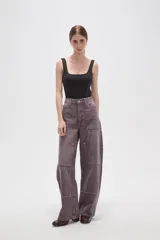 Pantalon de jean estilo barrel con tiro alto, diseño de paneles reforzados en las piernas y costuras visibles con remaches metálicos.