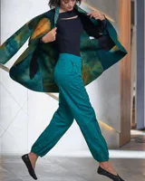 Pantalón babucha color beige de algodón, con corte a la cintura y piernas levemente amplias. Presenta textura de tablitas centrales y elásticos con broches inferiores que ajustan las piernas al tobillo.