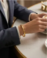 Pulsera tipo esclava rígida de acero con baño de oro, con diseño grabado de textura geométrica en forma de rombos.