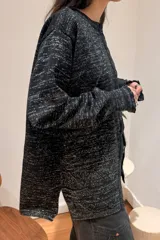 Camisa de punto con acabado brillante, color negro con destellos plateados, diseño de rombos, cuello redondo, cierre frontal con botones y mangas largas con puños ajustados.