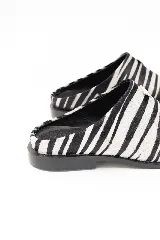 Zueco de cuero con estampado animal print de cebra, diseño de punta cuadrada y detalle metálico lateral. Cuenta con suela de caucho.