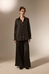 Camisa de poliéster con acabado satinado, de corte holgado, cuello camisero clásico, cierre frontal con botones y mangas largas con puños.