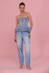 Pantalón jean de mujer en tono azul claro, con aplicación de cristales y pedrería en los laterales que aportan un toque sofisticado y luminoso.