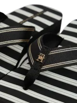 Ojotas de mujer con plataforma tipo cuña, suela EVA dentada y tiras de textil trenzado a rayas negras y blancas. Presentan una insignia con monograma TH en la tira del dedo.