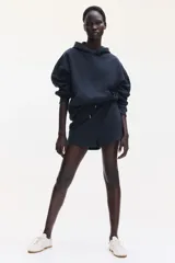 Canguro negro con capucha de doble capa, hombros caídos, bolsillo canguro y puños y bajo acanalados. Interior cepillado suave.