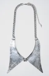 Collar dorado de aleación de metales con dije grande de forma triangular con puntas y flor al centro.
