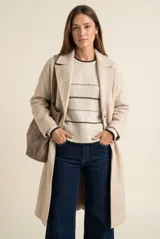 Tapado largo de corte oversize en color beige, con solapas clásicas y cierre frontal con botones. Presenta un diseño minimalista y elegante, ideal para un look sofisticado.