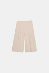 Bermuda larga de tiro medio en color beige, con diseño de pinzas frontales y costuras marcadas. Presenta un corte amplio y cierre lateral con cremallera oculta.