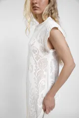 Vestido largo de crochet color crudo, con mangas cortas con volados y aberturas laterales, confeccionado en tejido calado de algodón con diseño ornamentado.