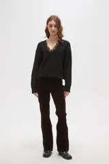 Sweater negro de punto con escote en V profundo y detalle de encaje en el borde del cuello. Presenta mangas largas con puños acanalados y un corte holgado.