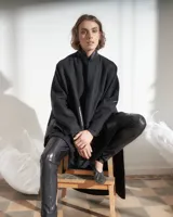 Capa negra de paño de lana con cuello mao y cierre frontal con ganchos ocultos. Estampado serigráfico negro brillante en cuerpo y cuello.