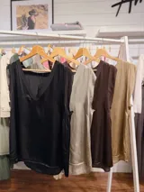 Blusa sin mangas de satén negro con escote en V profundo y terminaciones en contraste. Presenta un diseño fluido y elegante con corte recto.