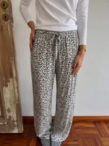 Pantalón tipo pijama de corte holgado y pernera recta, con estampado animal print tipo dálmata en blanco y negro, cintura elástica con cordón de ajuste y bolsillos laterales.