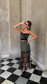 Falda asimétrica de tejido lurex negro y dorado, con pretina elástica y apliques de crochet en el ruedo.