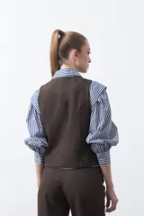 Chaleco sastrero color marrón oscuro, con escote en V, cierre frontal de botones y pinzas de entalle.