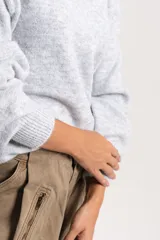 Buzo tejido de punto con diseño liso, corte oversize, cuello redondo y mangas largas con puños acanalados.