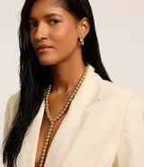 Conjunto de collar tipo lazo y aros tipo argolla, confeccionados en metal dorado con detalles de esferas.