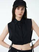 Top negro sin mangas con cuello camisero y cierre con botones.