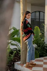 Cárdigan negro de tejido de punto con bordados de rosas rojas y hojas verdes. Presenta detalles bordados multicolores en hombros y puños.