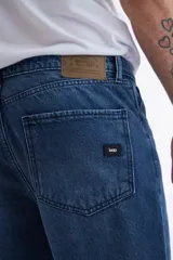 Jean azul oscuro de corte recto, tiro medio y largo a la altura del tobillo.