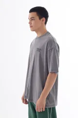 Remera gris con efecto acid wash, corte oversize y estampa en la espalda con personajes de dibujos animados (Bob Esponja, Itchy, Peppa Pig y Bart Simpson) con fajos de billetes.