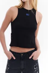 Top musculosa blanco de canalé con cuello redondo, corte ajustado y detalle de botones a presión en el lateral.