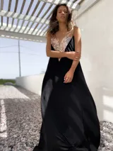 Vestido largo de fiesta color negro, con corte holgado y escote en V profundo decorado con lentejuelas doradas.