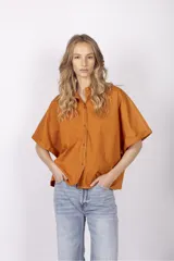 Camisa color ladrillo de corte holgado, con cuello camisero, mangas cortas con dobladillo y costuras a contratono.