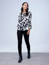 Blusa de gasa satén estampada con diseño animal print en tonos naranja y negro, de la marca Ninety. Tiene mangas tres cuartos y cuello redondo.