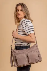 Bandolera de tafeta impermeable color beige, con dos bolsillos frontales con cierre y correa regulable. Diseño práctico y liviano ideal para uso diario.