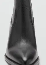Botín de cuero vacuno color negro, con diseño de estilo western, punta fina y tacón bloque de 6,5 cm. Cuenta con cierre de cremallera lateral.