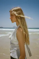 Top de cuello halter con escote drapeado, confeccionado en tejido satinado metalizado con acabado brillante.